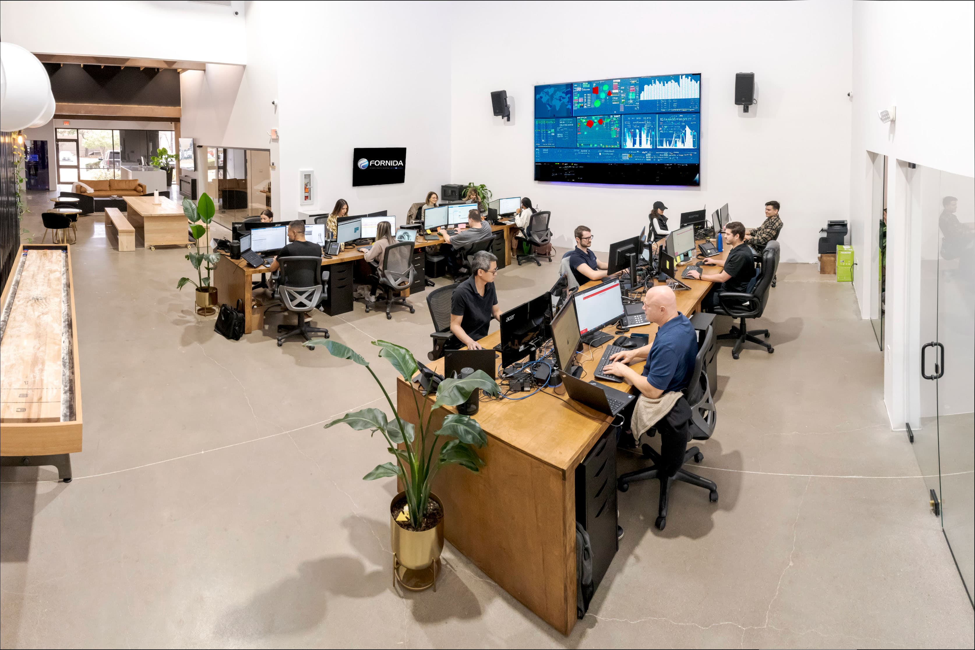 Fornida Network Operations Center floor with engineers at workstations and a wall-mounted operations dashboard